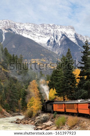 An Antique Steam Engine and Train Traveling Through the Rocky Mountains in the Fall