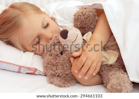 Adorable little girl sleeping in bed with her teddy bear
