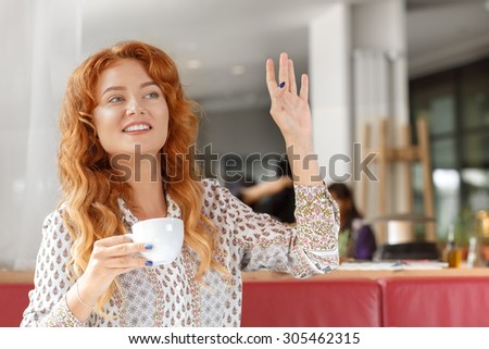 Red-haired girl drinking coffee in a bar