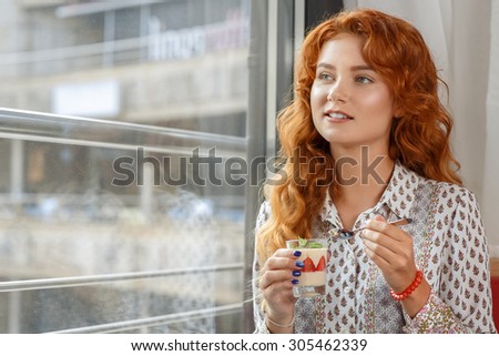 Red-haired girl drinking coffee in a bar