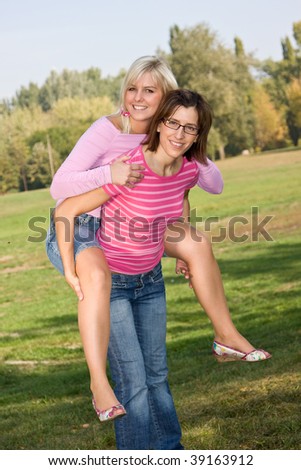 girl piggybacking her sister in the park