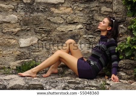 barefoot woman sunbathing on a rock