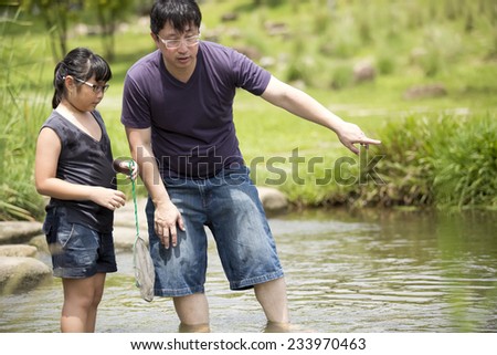 Young Asian father and daughter bonding catching fishes in river