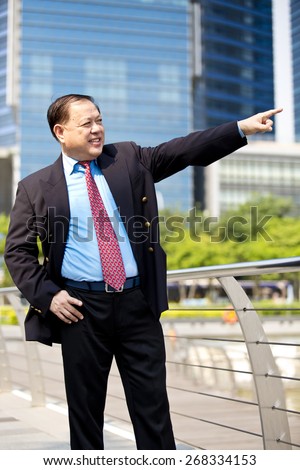 Asian business man in suit pointing to a direction