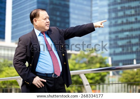 Asian business man in suit pointing to a direction