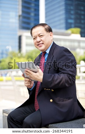 Asian businessman in suit using tablet