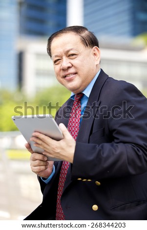 Asian businessman in suit using tablet