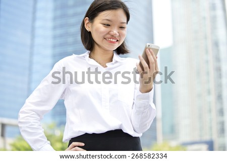 Asian young female executive smiling and looking at phone