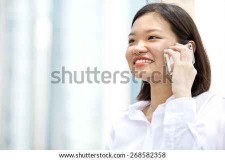 Asian young female executive smiling and talking on phone