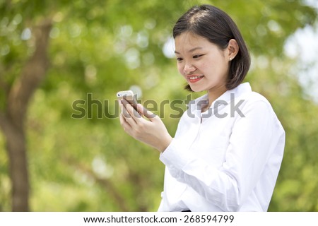 Asian young female executive smiling and looking at phone