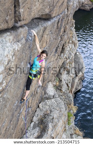 Female rock climber hanging over the abyss. Brave and confident female rock climber enjoys hanging on her hand over the deep abyss