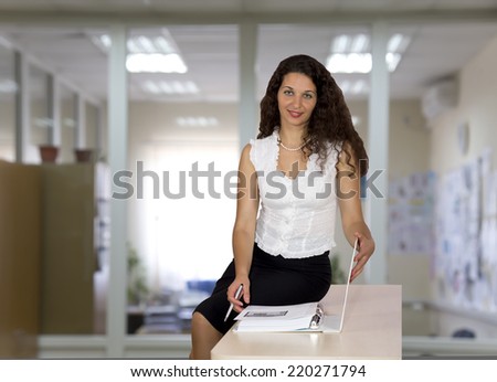 Nice female business consultant. Female business coach or consultant is sitting on the table, keeping large workbook and looking into the camera