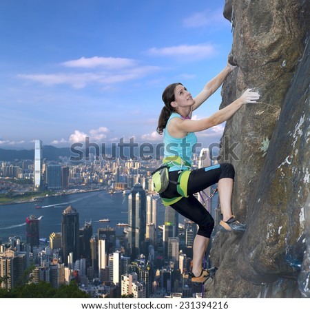 Female extreme climber conquers steep rock against modern urban landscape on the background