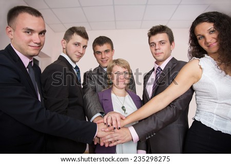 Friendly harmonious business team. Six business people join hands and smiling. Focus is on hands, but face expression is recognizable