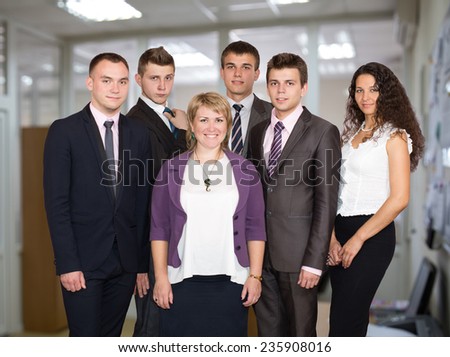 Happy business team in the open space office background.  Six people dressed in line with business dress code enjoy working together in the open space office
