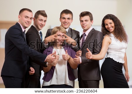Group of laughing business people. Six business people make funny gestures. The stay inside of office interior and dressed according to business dress code.