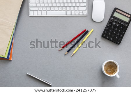 Office workplace at morning. Well ordered workspace on the grey wooden table with keyboard, pens, coffee mug and other business supplies