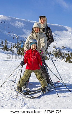 Family of three people learns skiing together. Happy, smiling, joyful