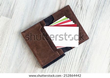 Blank business card. Conceptual composition with leather business-card folder, stack of colorful business cards and white blank business card on the foreground