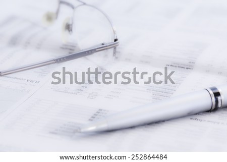 Business newspaper and glasses. Conceptual image of opened newspaper with stock exchange data, glasses and pen. Image intentionally softened in order to be a perfect light background for your titles