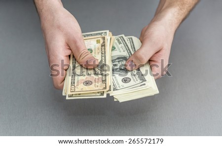 Counting large stack of cash notes.\
Male hands holding stack of US cash notes.