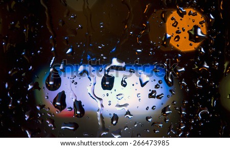 Rain drops and neon lights.\
Close-up image of large rain drops on glass surface with neon lights on background