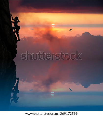 Silhouette of elegant female climber with lake and dusk. Slim woman athlete ascending rock wall above blue lake mountains and vivid red sunset on the background