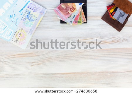 Desk of frequent voyager. Travel background with essential tourist items on wooden desk passport international with entry stamps and visas exotic currency credit card from above view