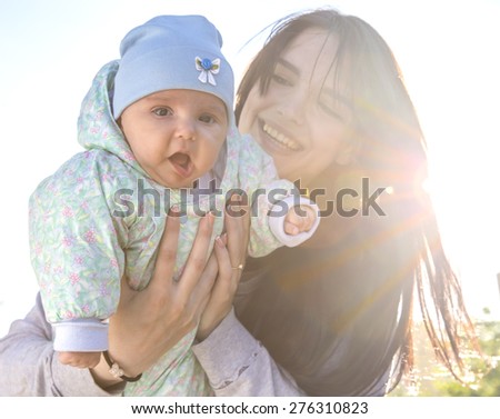 Mother and baby with back-light. Portrait of beautiful happy smiling lady mother holding infant little baby in her hands back light colorful sunbeam