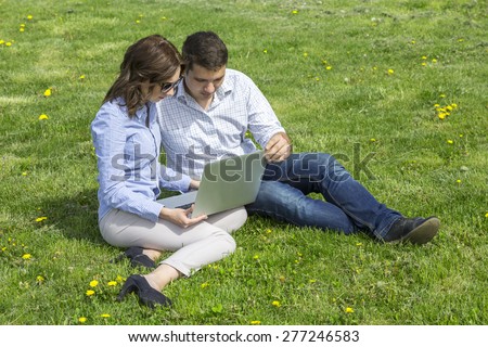 Young people working out. Man and woman casual dress code pant jeans shirt sitting on grass lawn working with laptop computer students learning businessman out of office