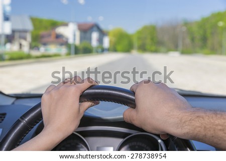 Driving car together.\
Male and female hands keeping steering wheel car highway background blue sky green forest