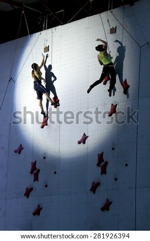 Female athletes jumping to finish point at speed climbing track in the round spotlight spot. National Climbing Championship, Dnepropetrovsk, Ukraine, May 23, 2015, Speed climbing, Female Final