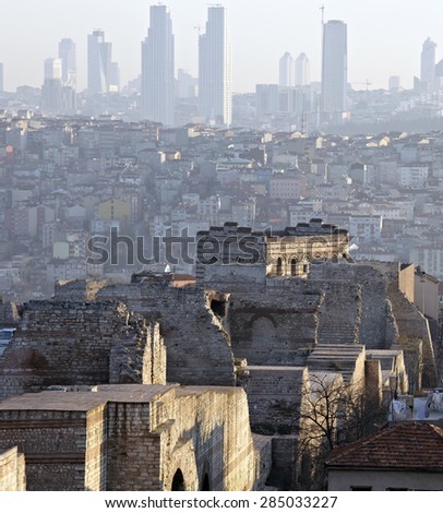 History meets nowadays. Ancient ruins of Theodora Byzantine Wall in Istanbul and modern skyline of buildings on background at soft sunrise