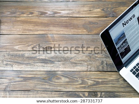 Digital subscription on rough wooden desk concept.\
Handcrafted natural wooden texture table with large copy space and cropped laptop with world news page on screen