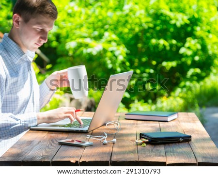 Hardworking man inspired with nature. Businessman working on laptop with serious inspired face on green terrace of suburban cottage at brown natural timber wood desk back light sun background