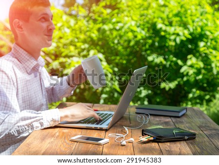 Working man inspired with nature.\
Businessman working on laptop with happy inspired face on green terrace of suburban cottage at brown natural timber wood desk back light sun from behind
