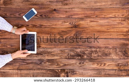 Man holding tablet PC sitting at vintage handcrafted wooden desk