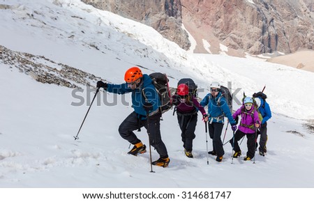 People traveling in mountains Large group of tourists of different sex ethnic nation race age young and old man woman walking up wild Snow Glacier terrain Steep Mountain Landscape in Background