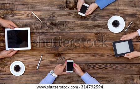 High-Tech Human Generation Lifestyle\
Hands of Group Young People Sitting At Natural Vintage Looking Wood Desk Using Variety Electronic Gadgets