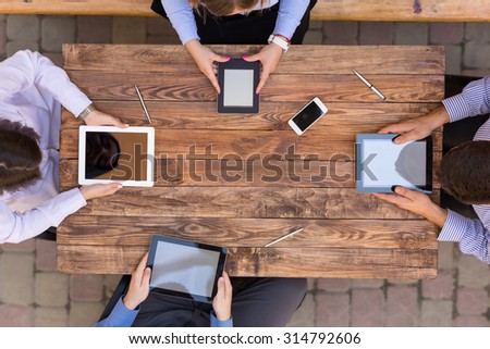 High-Tech Human Generation Lifestyle Hands of Group Young People Sitting At Natural Vintage Looking Wood Desk Using Variety Electronic Gadgets