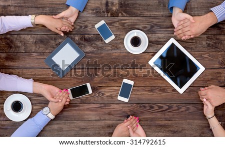 Business Team Unity Group of People at Vintage Wood Table Holding Hands Round Top View High-Tech Electronic Gadgets on Desk Tablet Computer Coffee Telephone