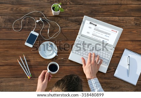 Writer Working on Computer at Wooden Desk\
Top View of Man Typing on Laptop and Holding Coffee Mug at Warm Natural Wood Table with Electronic Gadgets and Stationery Tools for Every Day Life