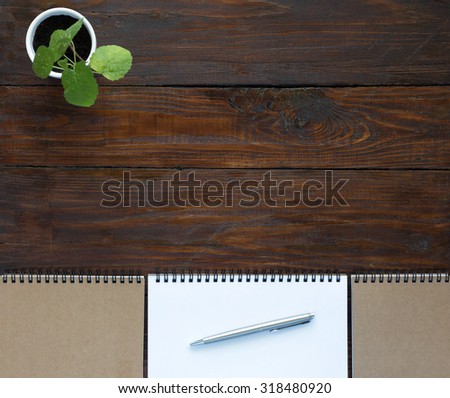 Dark Brown Wooden Desk with Sketchbooks and Flower\
Top View of Natural Wood Background Line of Opened and Folded Notepads in Serene Beige Tones Green Plant in Right Corner and Executive Class Pen