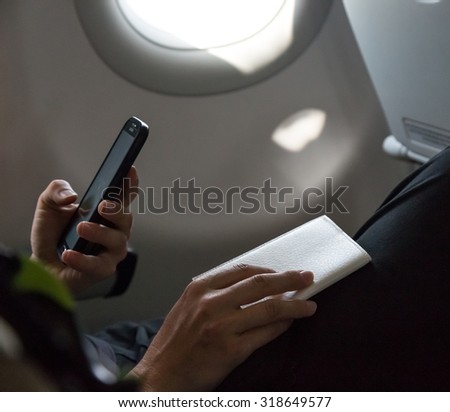 Air Flight Passenger Sitting in Aircraft\
Casual Clothing Woman in Plane Seat Preparing her Documents for Immigration Formalities Male Hand Holding Telephone on Foreground