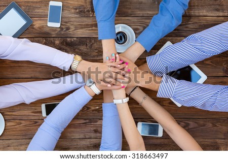 Business Team Unity\
Group of People at Vintage Wood Table Holding Hands Round Top View High-Tech Electronic Gadgets on Desk Tablet Computer Coffee Telephone