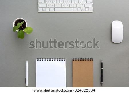 Grey Wooden Desk with Stationery and Electronics Classic Tone Wood Background Opened and Folded Beige Notepads Small Green Plant  Computer Mouse and Keyboard Top View