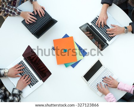 White Office Round Table and Men and Women Working on Computer Top View Casual Clothing Typing on Keyboard Many Laptops  Colorful Booklets