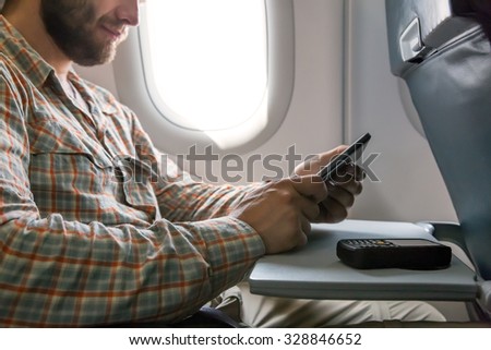 Hands of man browsing gadget in aircraft Person sitting inside airplane Window Seat Using Electronic Gadget Casual Clothing Bearded