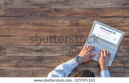 Man working on computer presentation sitting at unusual handcrafted rough wooden desk overhead top view soft sunlight large copy space
