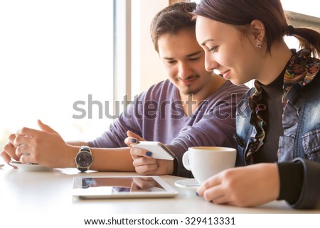 People at White Table of Coffee Shop Talking Smiling Using Electronic Devices